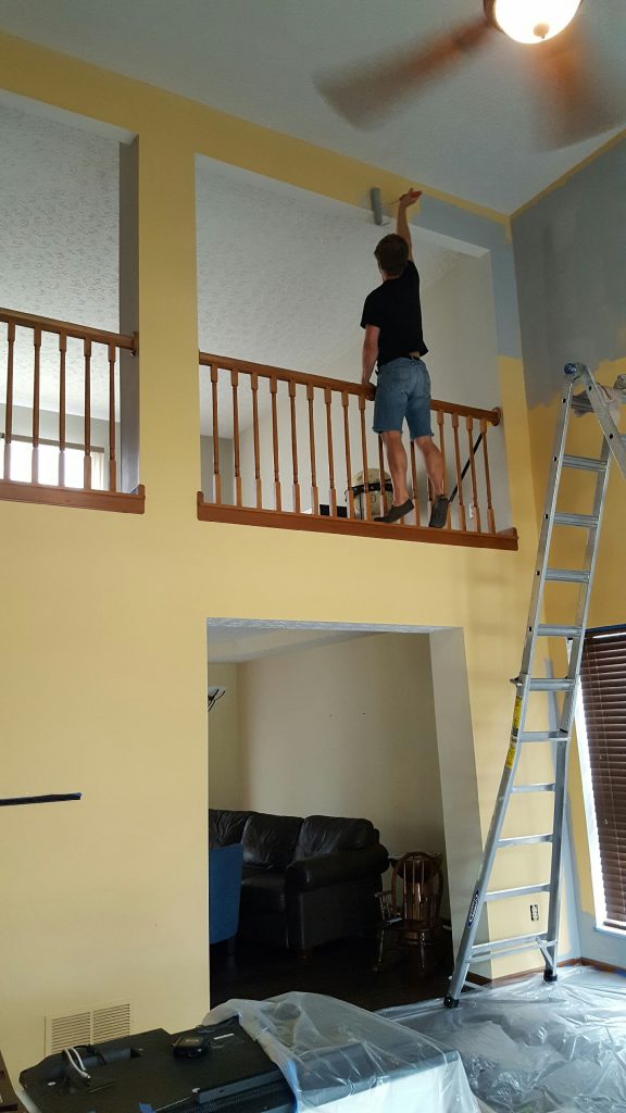 man painting great room with use of tall ladder