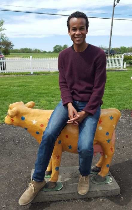 Black man sitting on top of cow statue at Young Jersey's Dairy in Springfield, Ohio