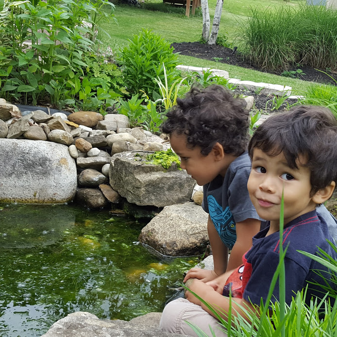 Two young kids playing in small pond in backyard of house