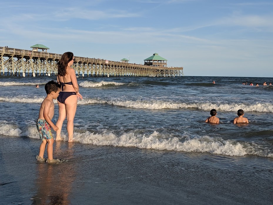 Kids in the water near the pier at Folly Beach in Charleston, South Carolina, as seen during our family road trip to South Carolina. 