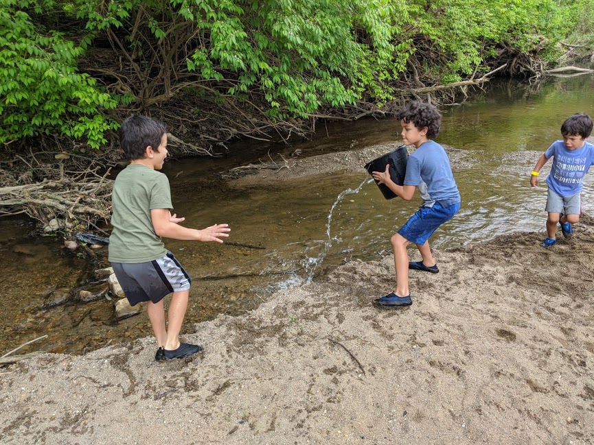 Kids throwing buckets of water at creek
