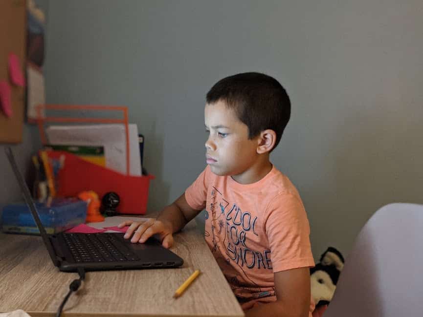 4th grader reading virtual school assignments from a computer