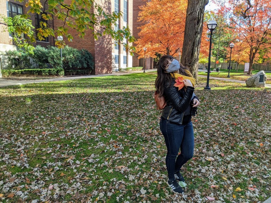 woman holding fall foliage on the University of Michigan campus in Ann Arbor