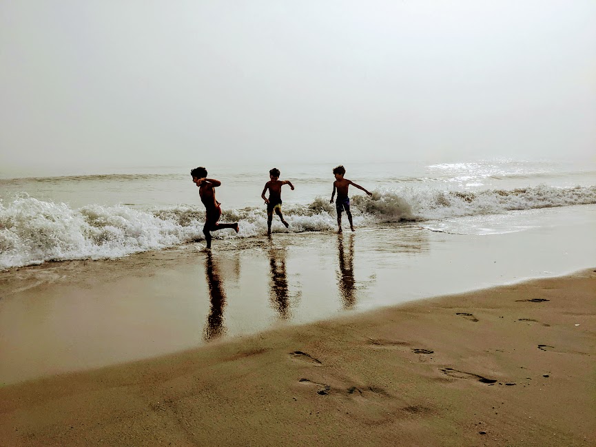 Three kids running on the Carolina Beach shore