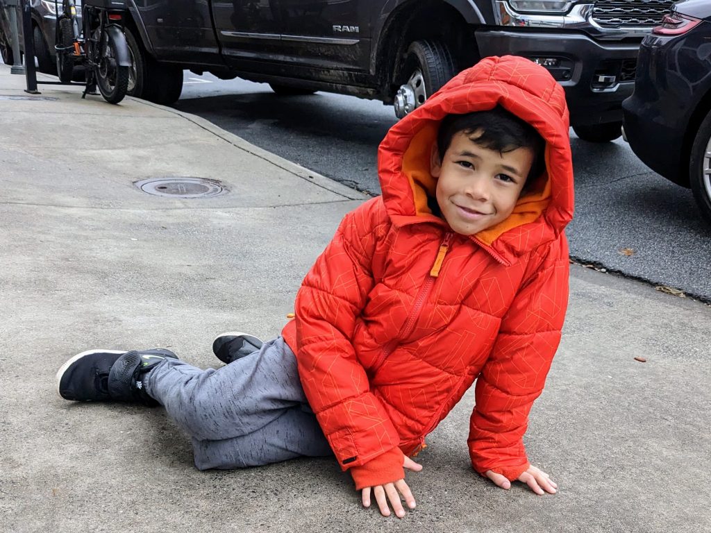 tired kid sitting on a downtown Asheville sidewalk 