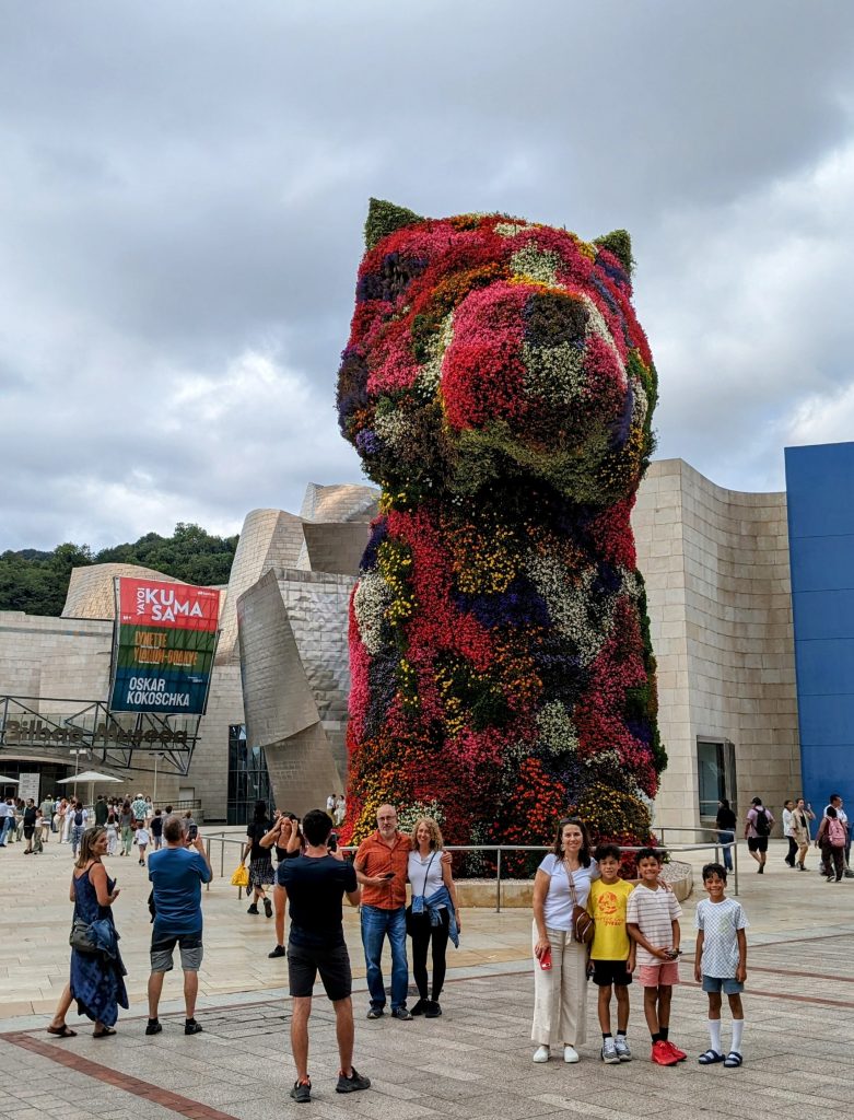 Families pose near a olorful puppy flower sculpture outside Bilbao's Guggenheim Museum. 