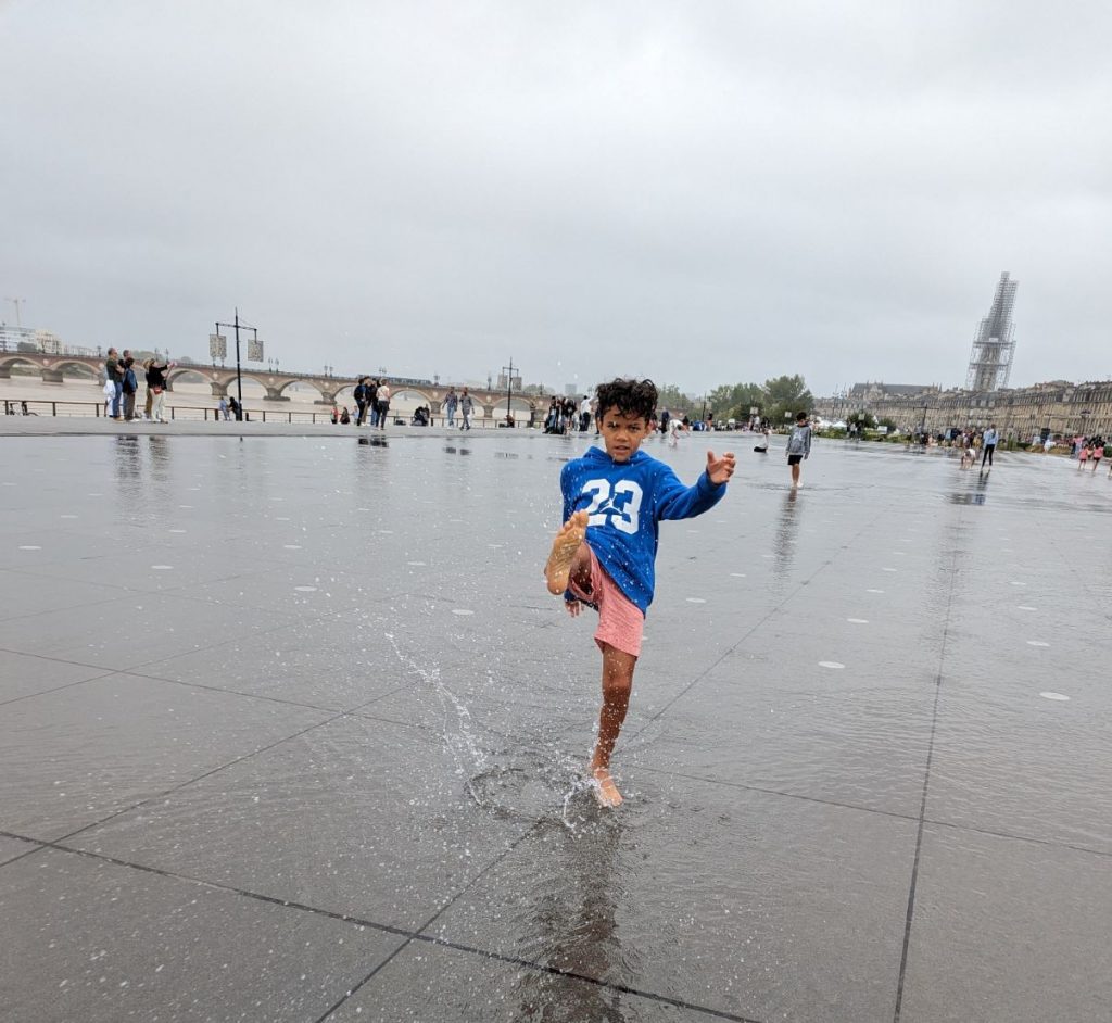 Kid kicking water in the world's largest reflection pool in Bordeaux, France. 