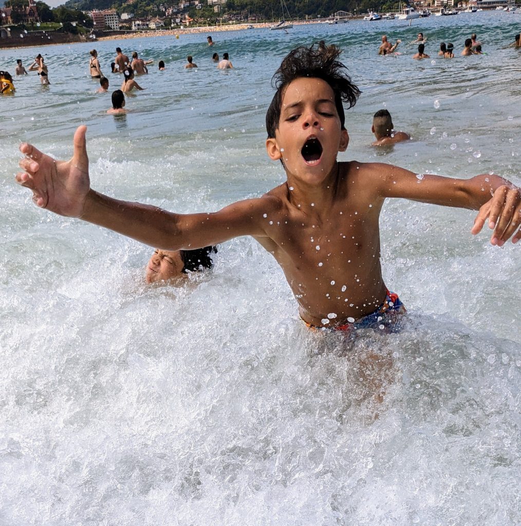 Kid jumping waves in the ocean near San Sebastian, Spain 