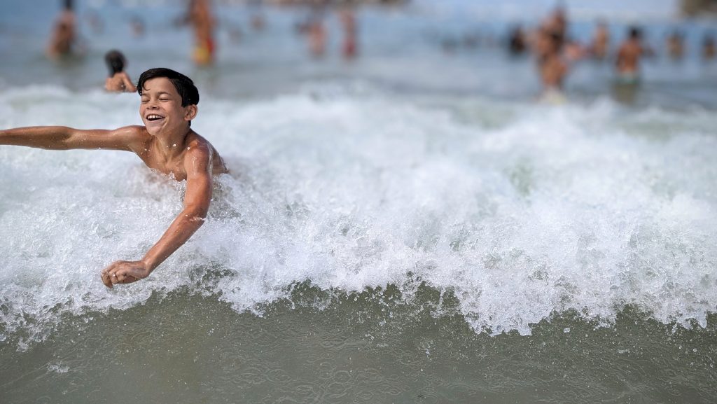 Kid smiling while jumping waves in the ocean near San Sebastian, Spain 