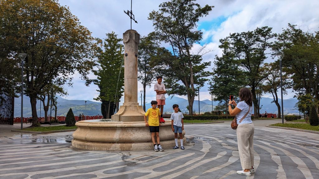 A family posing in front of a monument overlooking hills in Bilbao, Spain 