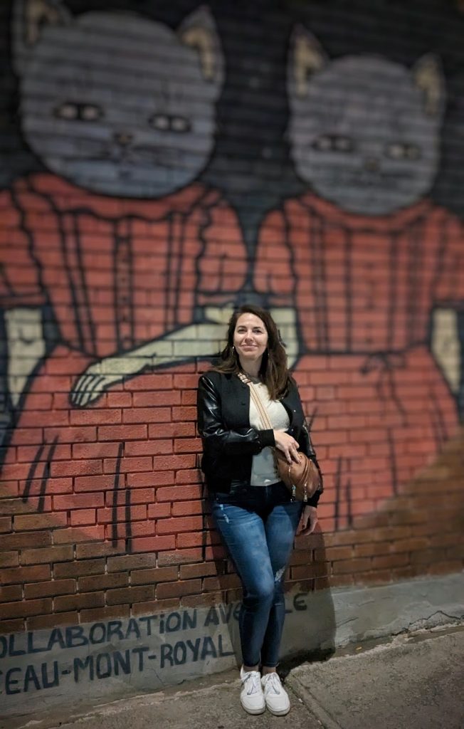 Amber posing in front of street art of cats in dresses in Le Plateau Montreal