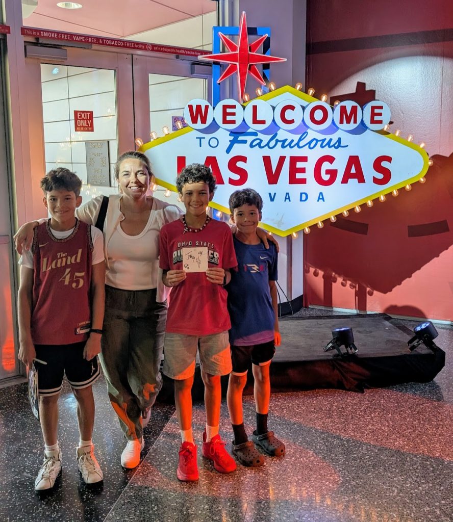 Family posing outside of Welcome to Las Vegas sign in Park MGM hotel. 